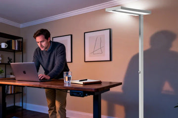 Hybrid worker's optimized spring home office setup featuring task lighting and ambient floor lamp with controlled natural daylight