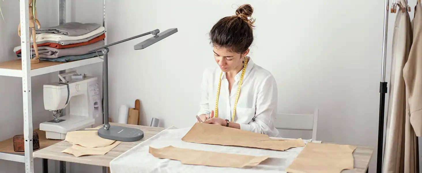 Fashion designer or seamstress working with pattern paper at a sewing table.slider_item_qEfc3c