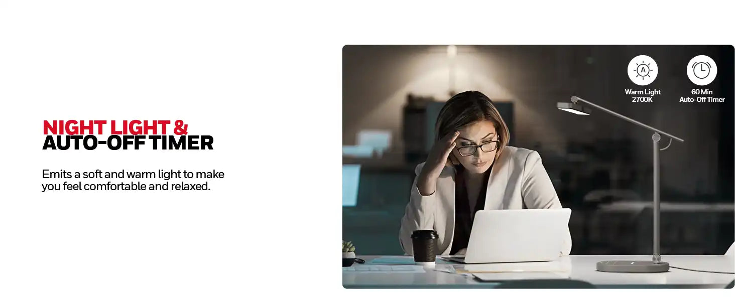 Person in a white blazer working at a laptop under a desk lamp.