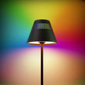 Black ribbed honeywell m1 rgb cordless table lamp with vertical slats casting warm glow on rainbow background